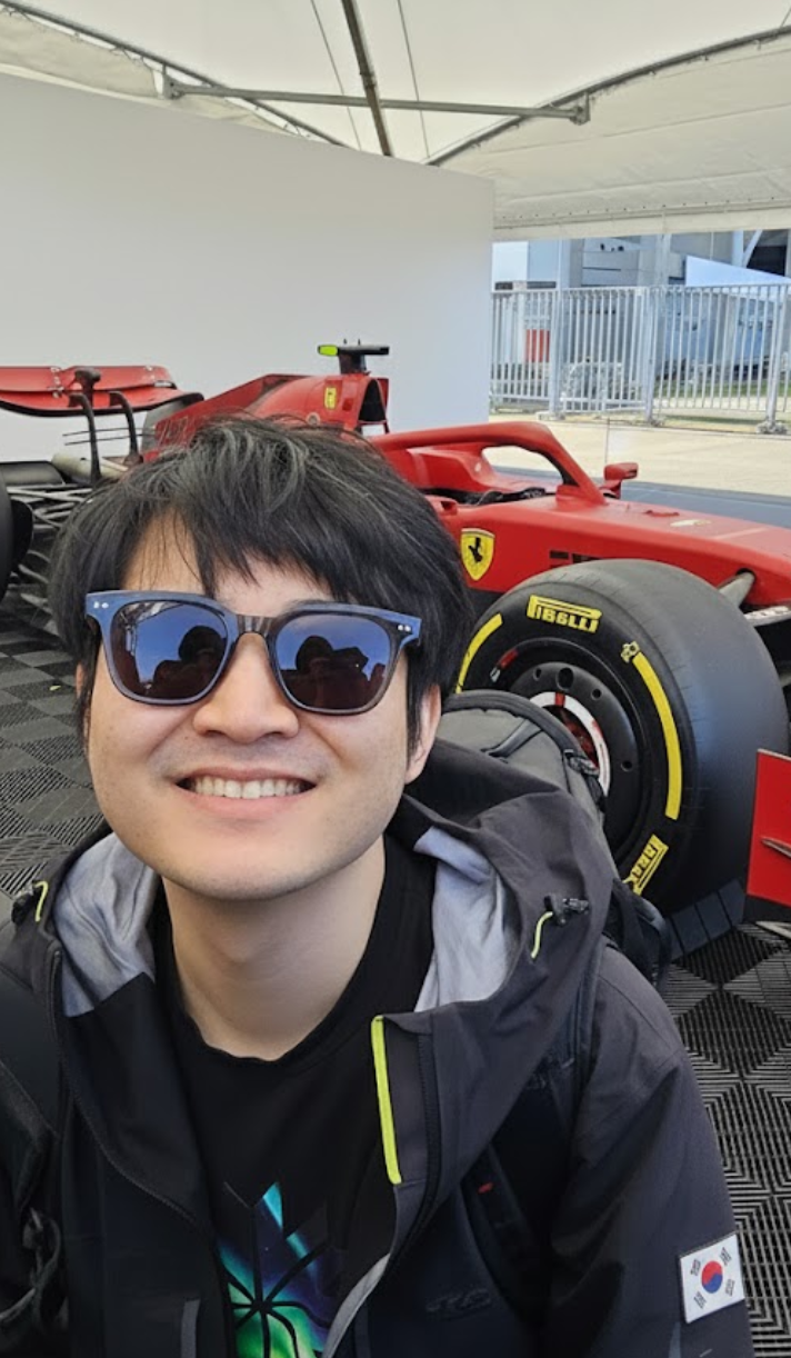 Milhan Kim smiling in front of a Ferrari Formula 1 car
